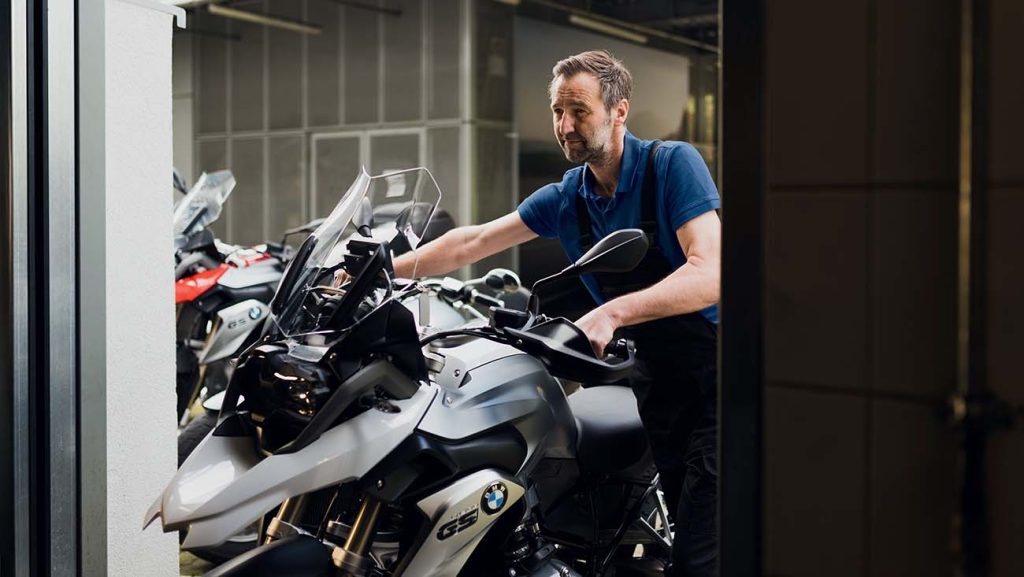 mécanicien qui pousse une moto dans le cadre de l'entretien BMW Motorrad