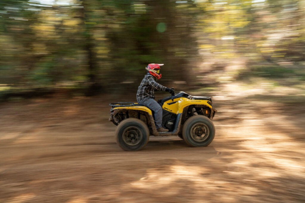 quad tout-terrain Can-am Outlander en situation de conduite hors route en forêt